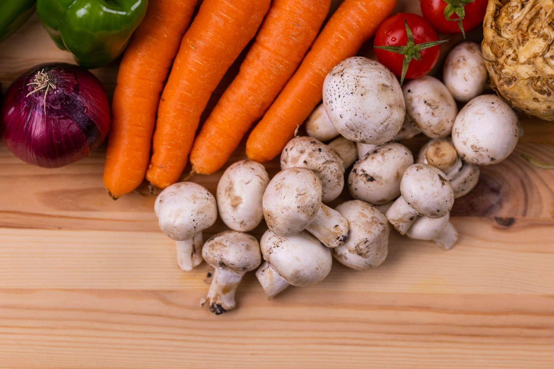 Des carottes et des gousses d’ail frais sur une table en bois clair