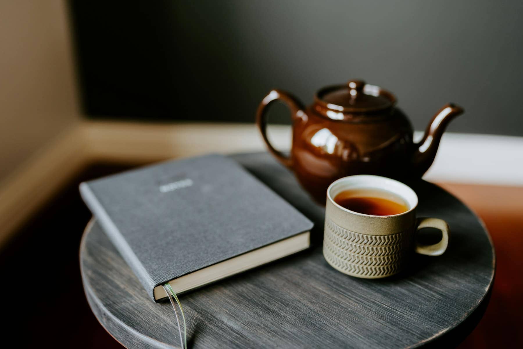 Une tasse de thé et un livre ouvert sur une table en bois